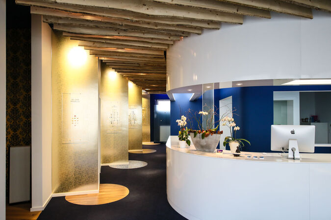 Modernes Empfangsbereich einer Praxis mit Holzdecke, Orchideen und stilvoller Beleuchtung.